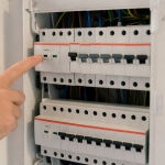 Doigt pointant un disjoncteur dans un tableau électrique