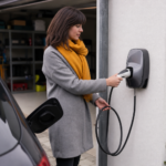 Femme branchant câble de recharge sur voiture électrique